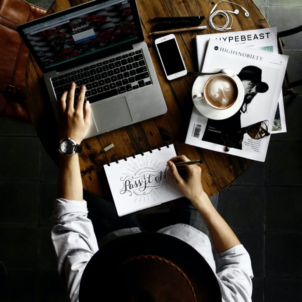 Persona diseñando con computadora y cuaderno